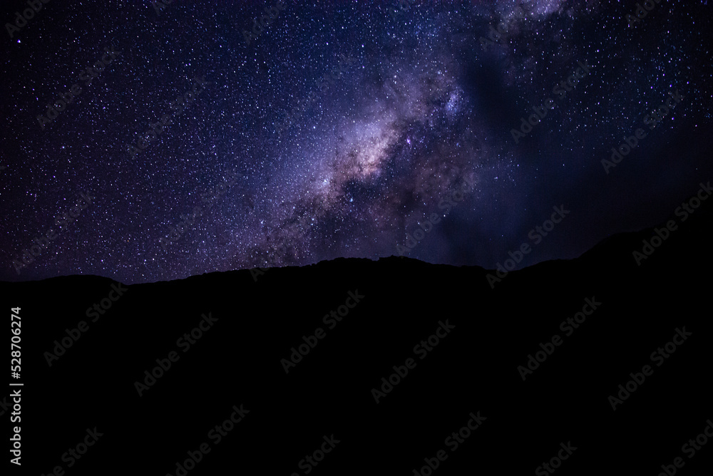 Beautiful background of night landscape with colorful Milky Way over the sky on the mountains. Starry sky with hills at summer. Beautiful Universe. Space background.