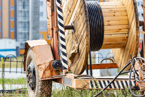 Wooden reel with high voltage cable mounted on a trailer for easy transport and stowage. Laying a high-voltage power cable in the ground. Laying of cables, laying of underground communications.