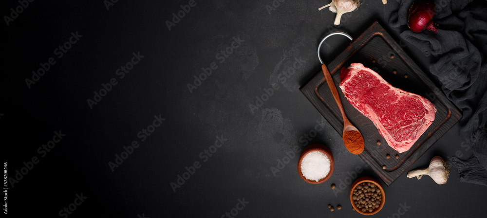 Raw juicy piece of beef meat on the bone lies on a wooden cutting board Raw juicy piece of beef meat on the bone lies on a wooden cutting board