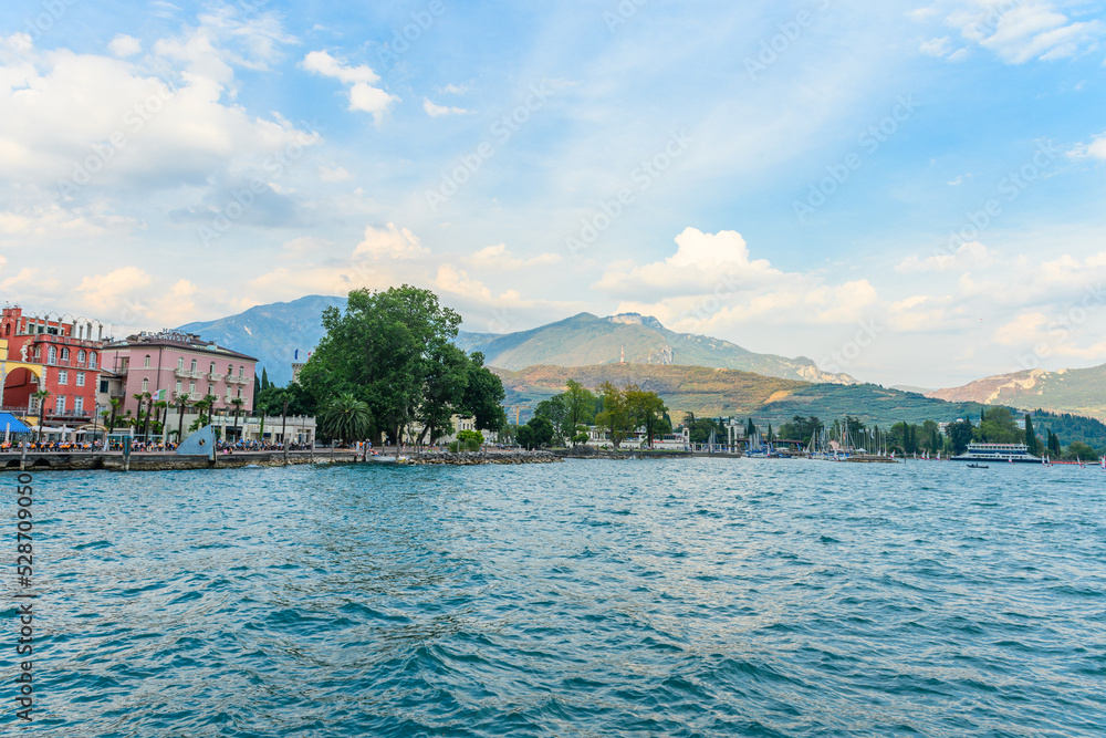 The beautiful Garda lake in Italy, seen from the Piazza ill Novembre square in the city of Riva del Garda, Trentino, Italy. It is a beautiful summer day, with a little bit of clouds.