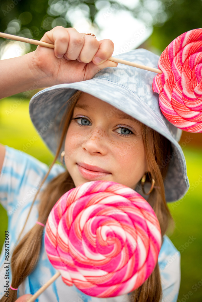 the child eats a bright lollipop. Beautiful girl model eats a bright