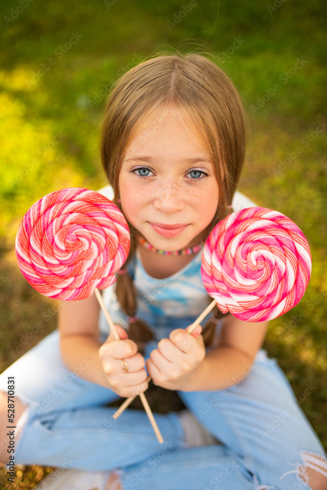 the child eats a bright lollipop. Beautiful girl model eats a bright lollipop. The child eats a