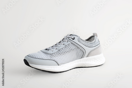 Sport shoes. Single light-colored sneaker for summer running. Shoe on light surface, side view