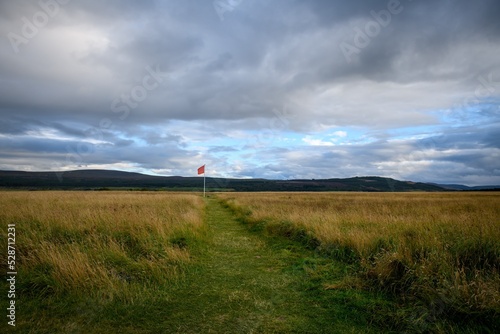 Culloden battlefield with a path leading to a red flag. Cloudy sky background. photo