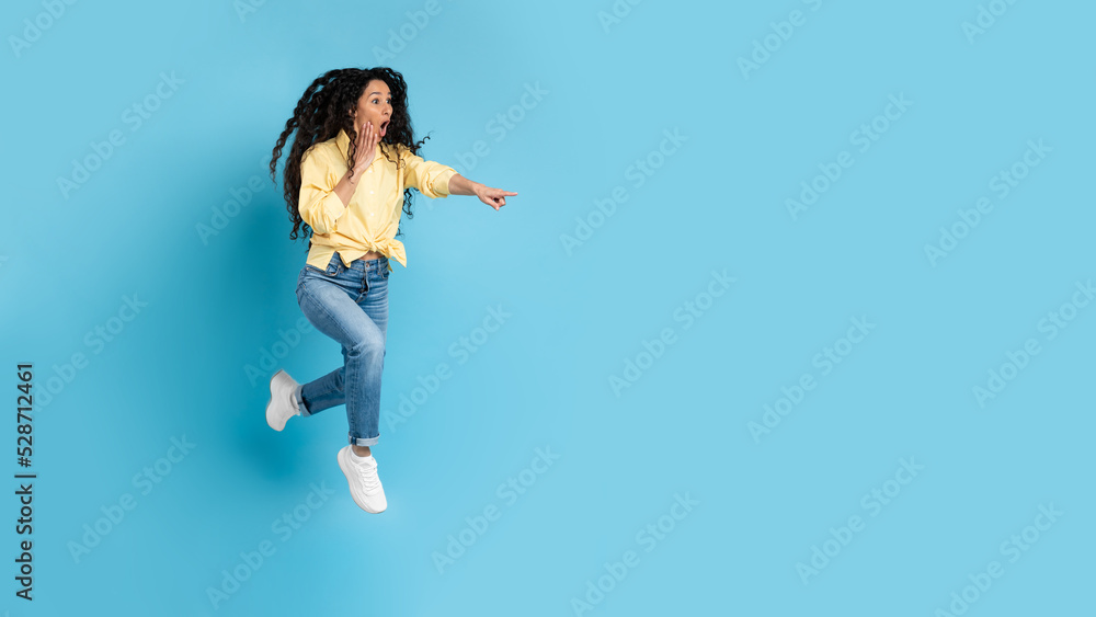 Shocked Woman Pointing Finger Aside Jumping Over Blue Background, Panorama