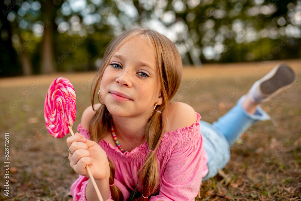 the child eats a bright lollipop. Beautiful girl model eats a bright