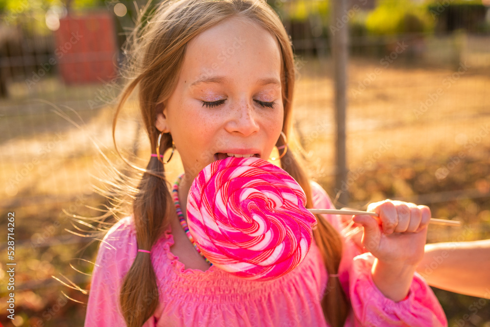 the child eats a bright lollipop. Beautiful girl model eats a bright