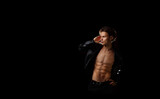 handsome macho man with a naked torso in a black leather jacket on a dark background