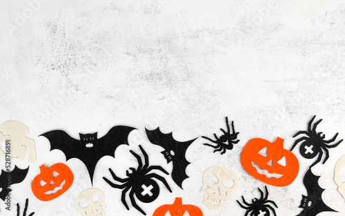 Minimalsitic halloween background with skulls,pumpkins,bats abd spiders on white concrete background. Invitation or card for october 31.Copy space photo