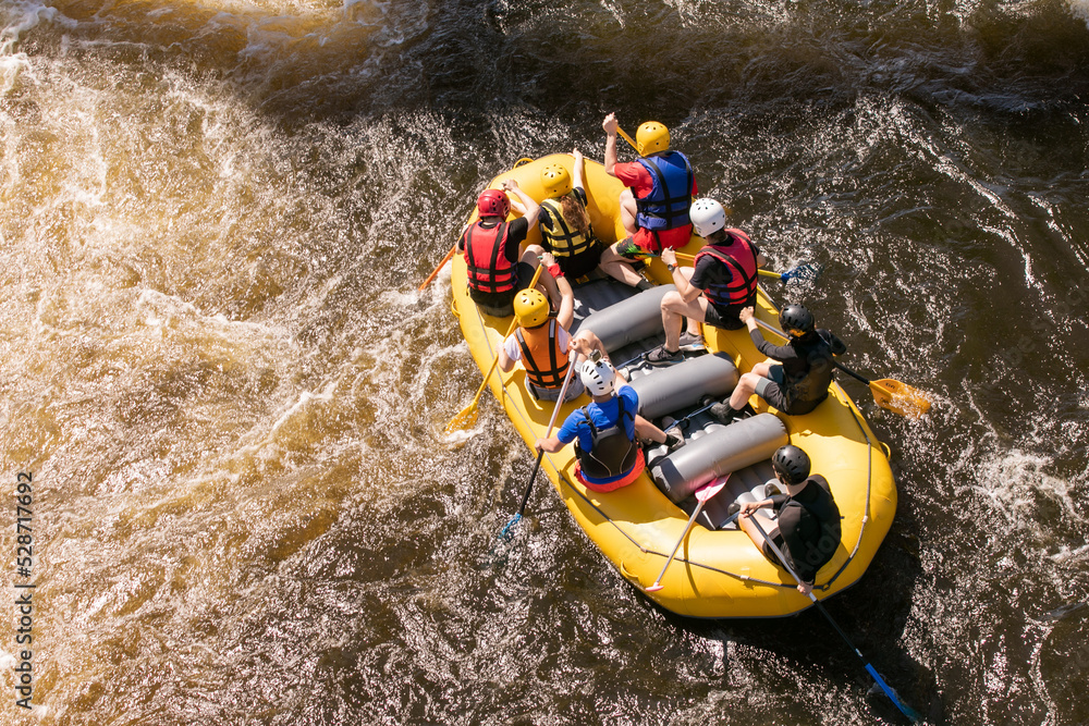 Top view of a rowers team with an oars overcomes rapids on a stormy river on an inflatable rafting boat - obrazy, fototapety, plakaty 