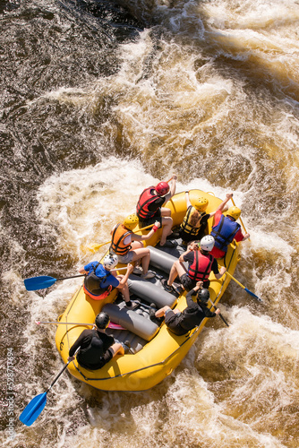 Top view of a rowers team with an oars overcomes rapids on a stormy river on an inflatable rafting boat