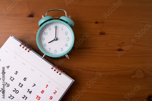 close up of calendar and alarm clock on the wooden table background, planning for business meeting or travel planning concept