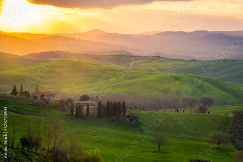 Sunrise over a lone farm in the middle of the hills of the Tuscany countryside   Italy
