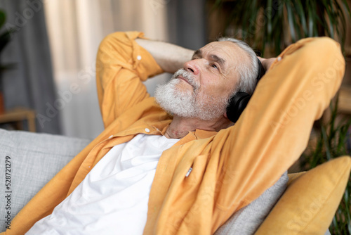 Relaxed elderly man enjoying newest wireless headset at home