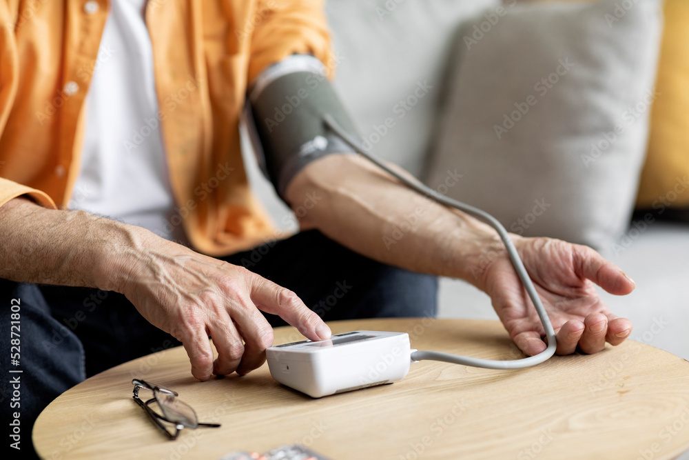 Unrecognizable senior man checking blood pressure at home