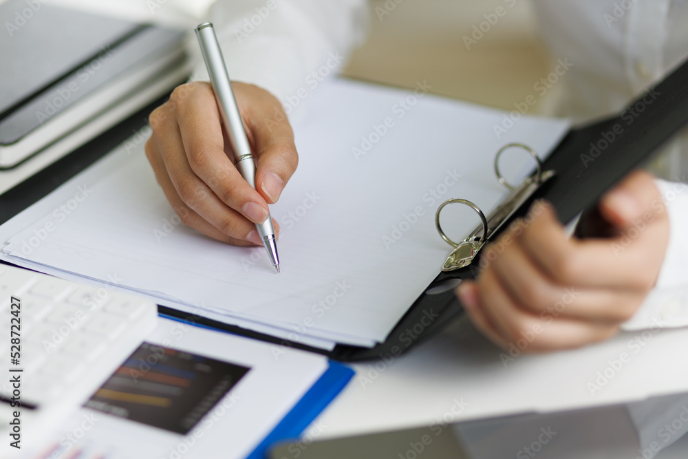 The secretary is writing the memo of the working message in the file. The secretary is writing the memo of the working message in the file.