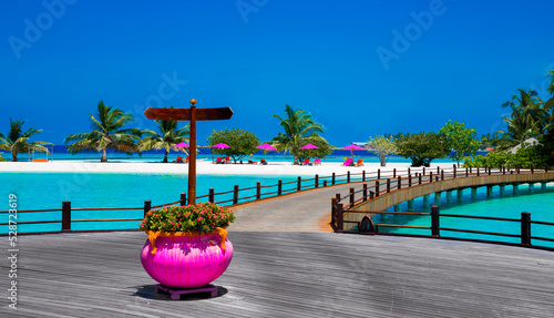Landscape on Maldives island, luxury water villas resort and wooden pier. Beautiful sky and ocean and beach with palms background for summer vacation holiday and travel concept. Luxury travel.