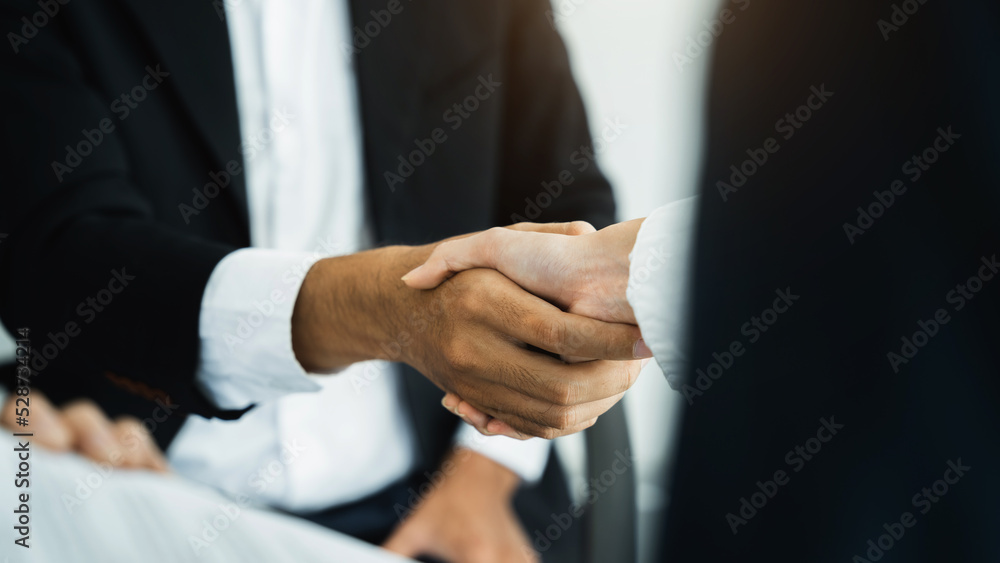 Business men and women shake hands confidently at an office meeting.