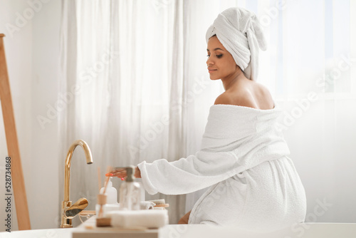 Relaxed Woman Enjoying Bodycare Rituals Using Cosmetics Sitting In Bathroom