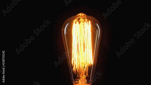 incandescent light bulb switched on isolated on black with copy space
