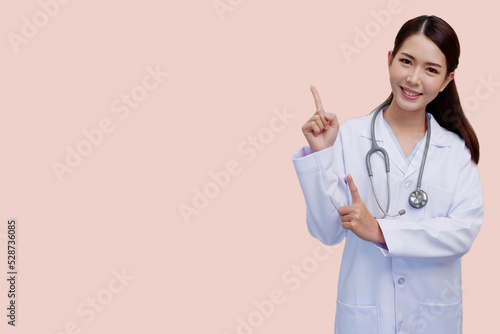 Asian female doctor smiling Standing pointing fingers to present wearing a white doctor s uniform with medical stethoscope on pink background medical concept.