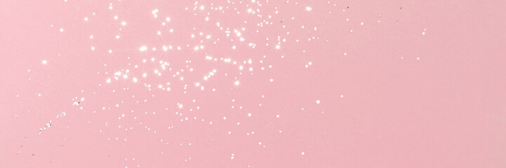 Sparkling silver glitter on pink background banner texture. Abstract holiday blurred lights header. Wide screen wallpaper. Panoramic web banner with copy space for design