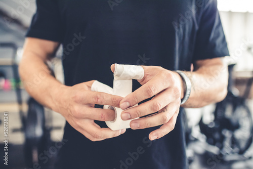 Cropped view of unrecognizable man boxer wrapping his hands indoors gym