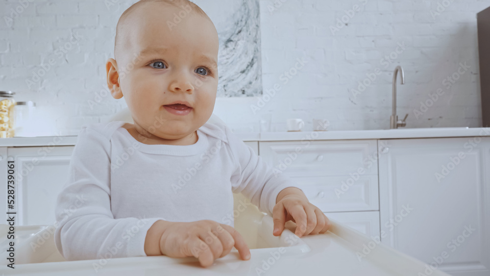 cheerful baby girl with blue eyes sitting in feeding chair cheerful baby girl with blue eyes sitting in feeding chair