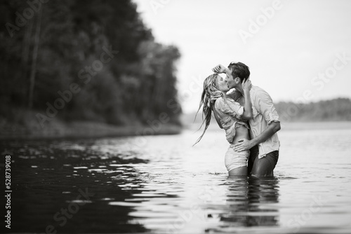 Guy and girl kiss standing in the water.