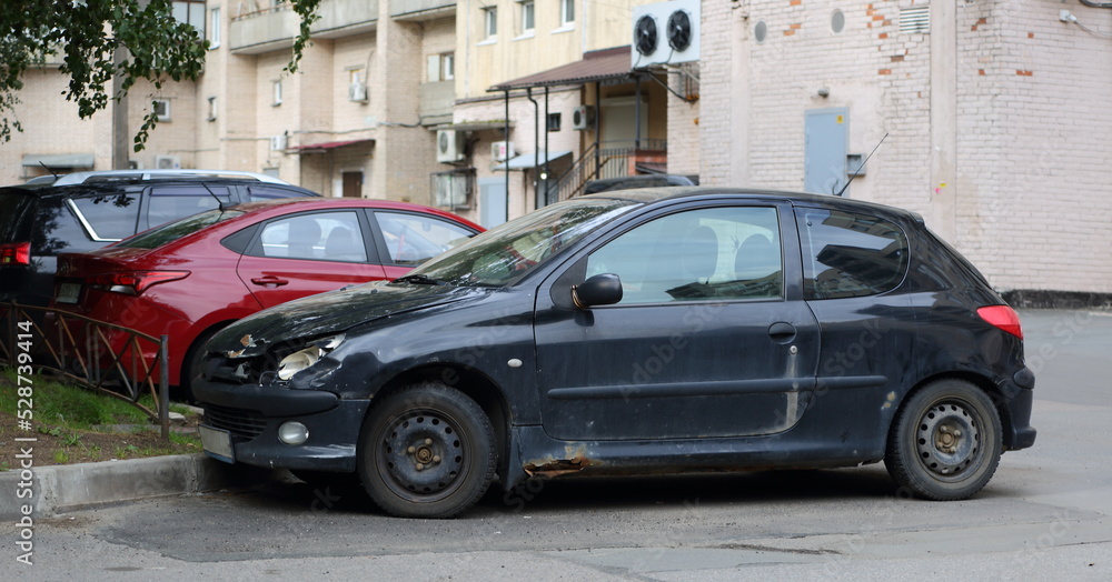 An old rusty broken car in the parking lot in the courtyard of a residential building, Prospekt, Bolshevikov, St. Petersburg, Russia, September 2022