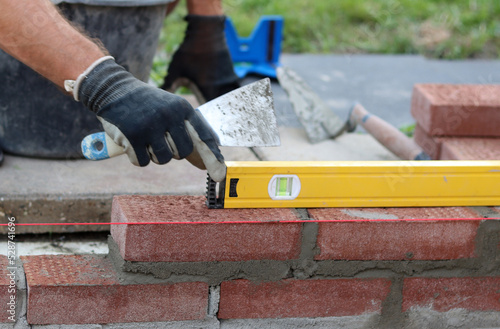 Close up photo of male hands holding red brick. Construction site concept. Professional build brick wall. 