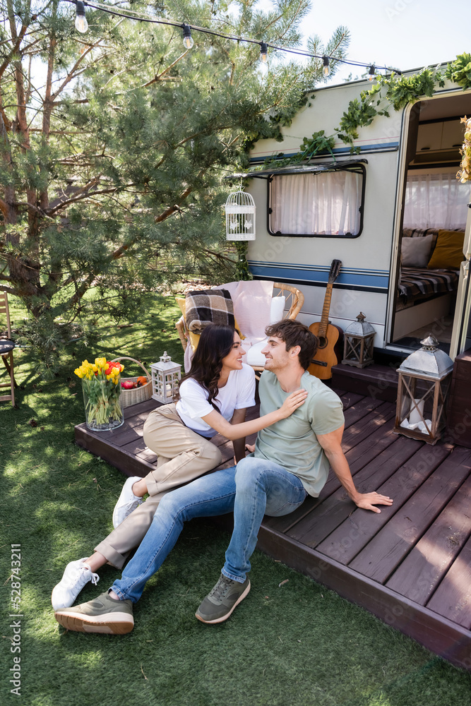 Side view of smiling woman touching boyfriend on terrace of camper van
