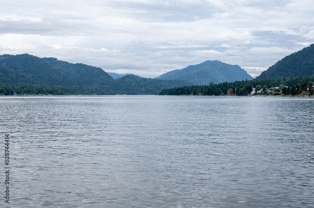 Landscape lake surrounded by mountains with dense forest. Shot taken from a boat