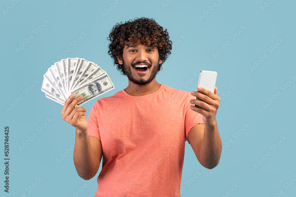 Happy eastern guy holding cell phone and cash Happy eastern guy holding cell phone and cash