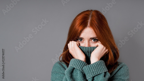 shy or embarrassed woman pulling turtleneck sweater over face photo