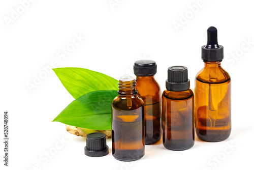 Ginger essential oil in bottle and fresh ginger with green leaf isolated on white background. The scientific name is zingiber officinale. Herbs for health care concept.