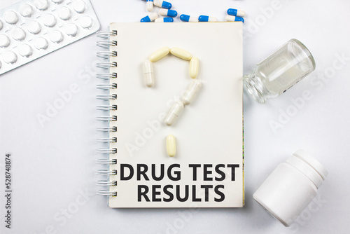 DRUG TEST RESULT on the notepad next to the pill question mark. Compulsory drug testing, pill abuse. photo