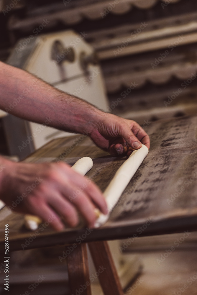 Baker's hands preparing baguettes for baking