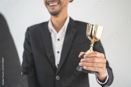 The hands of an employee receiving a golden cup reward from the company manager represent his performance in his career job reward.