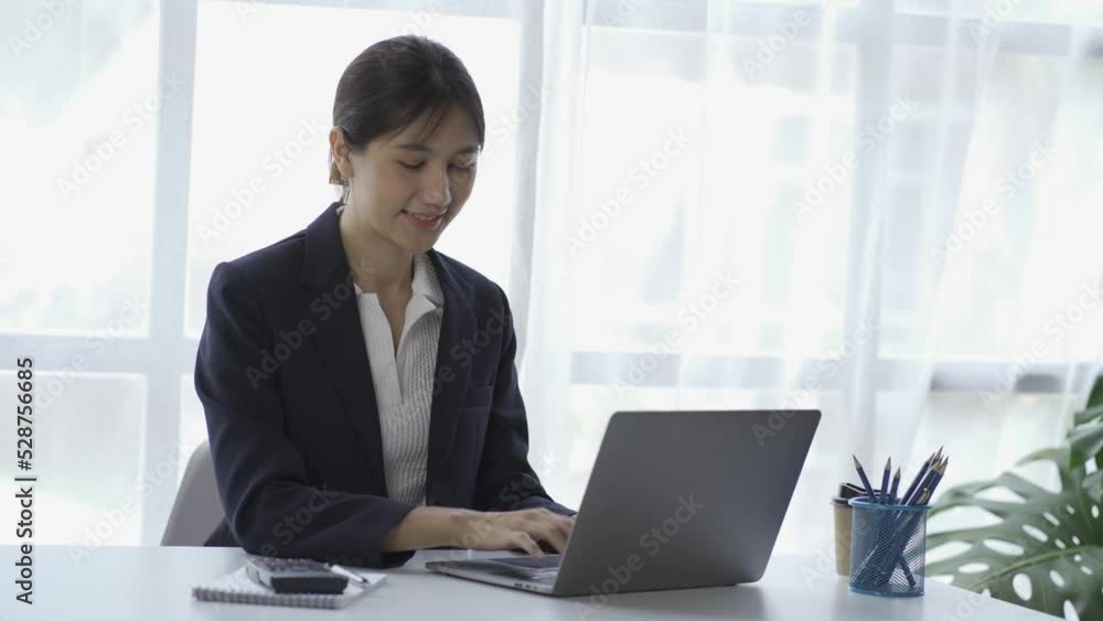 online business Asian female accountant working from home using laptop in meeting with smartphone, financial graphing calculator.