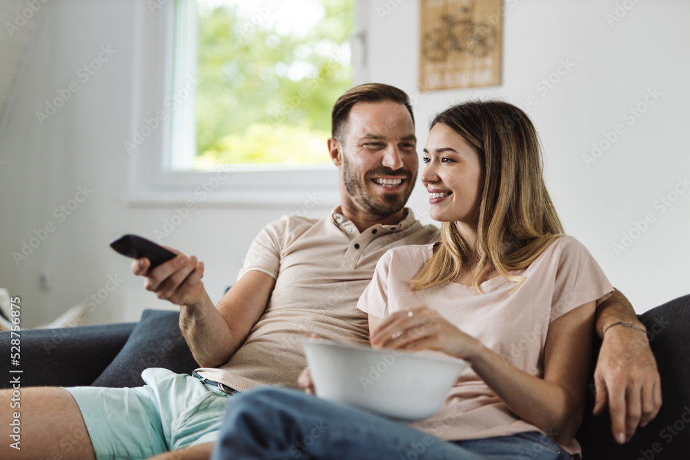 Happy young couple relaxing at home and watching television together Happy young couple relaxing at home and watching television together
