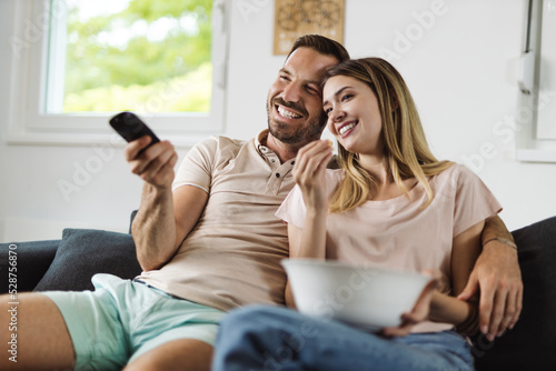 Happy young couple relaxing at home and watching television together