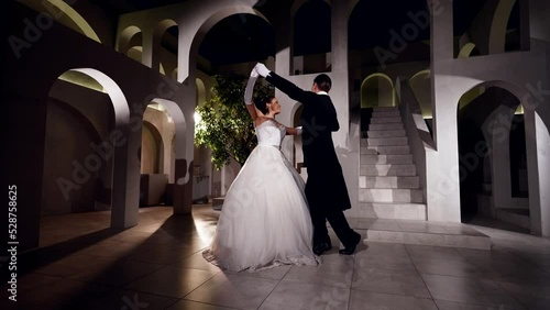 attractive woman and man are dancing viennese waltz in dark ballroom, romantic atmosphere