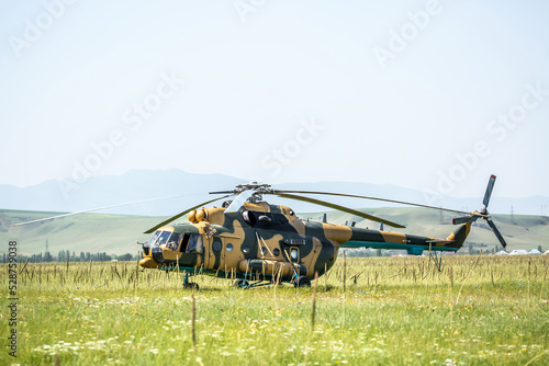 In the field is a military helicopter with soldiers. Armed conflict, fighting. Air armament and defense of the territory.