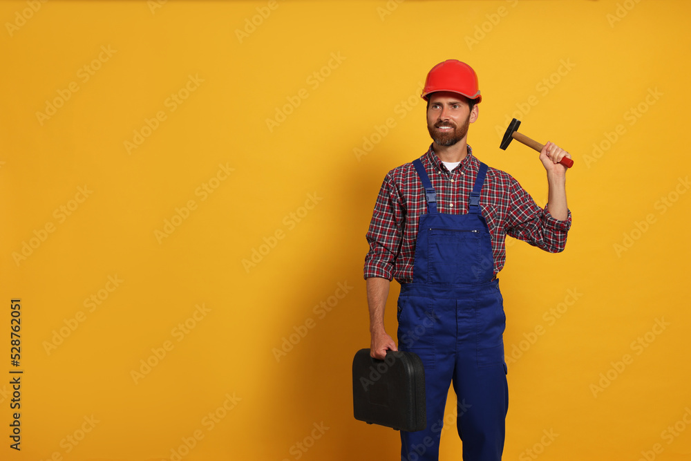 Professional builder in uniform with hammer and toolbox on yellow background, space for text