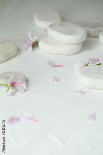 Spa stones and fresia flower on white table