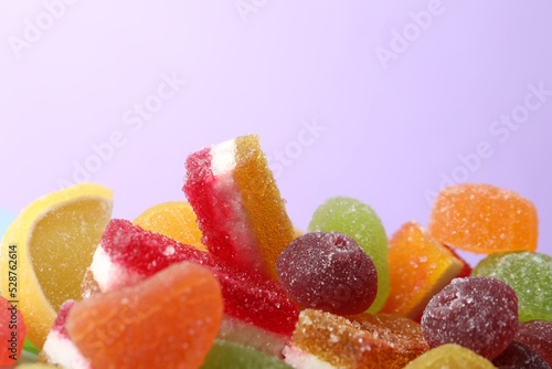 Pile of delicious bright jelly candies on violet background, closeup