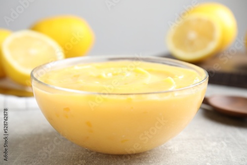 Delicious lemon curd in bowl on grey table, closeup