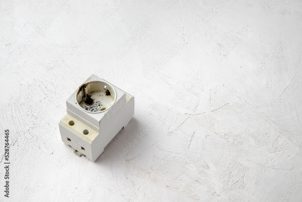 DIN rail socket after a short circuit in the power grid, gray concrete background, copy space. DIN rail socket after a short circuit in the power grid, gray concrete background, copy space.