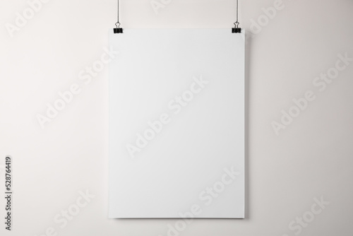White blank poster hanging near light wall